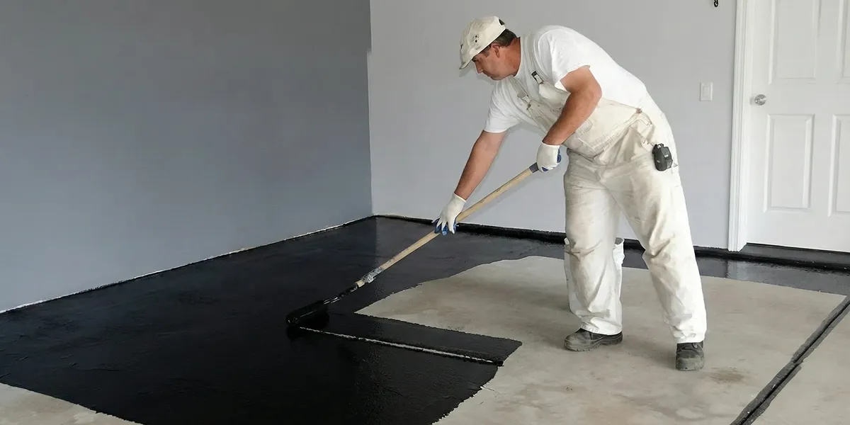 basement waterproofing professional applying waterproof coating to protect a basement floor in Philadelphia, PA